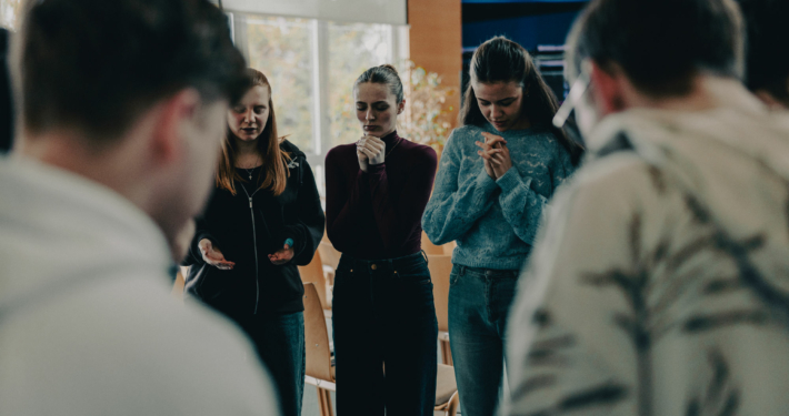 Three Female Students of the European Theological Seminary bowing their head in prayer